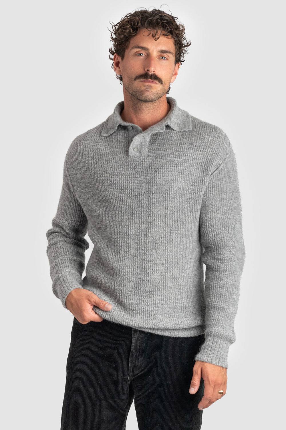 Man wearing a gray ribbed sweater over a collared shirt on a light gray background #colour_cool-grey